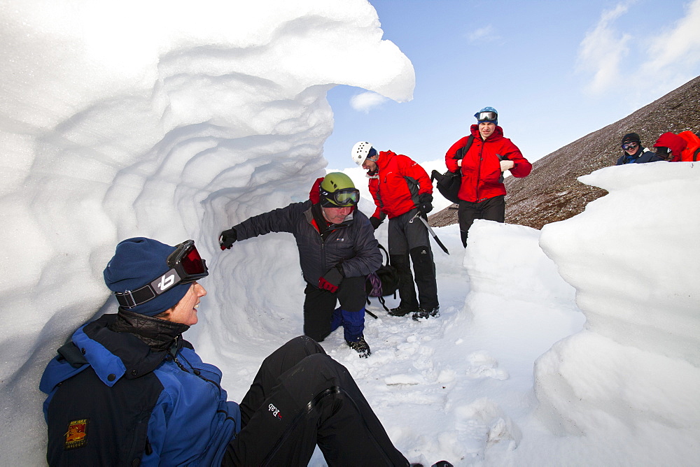 Mountaineers sheltering in an old snow hole in snow banked against an esker in Coire an Sneachda in the Cairngorms, Scotland, United Kingdom, Europe