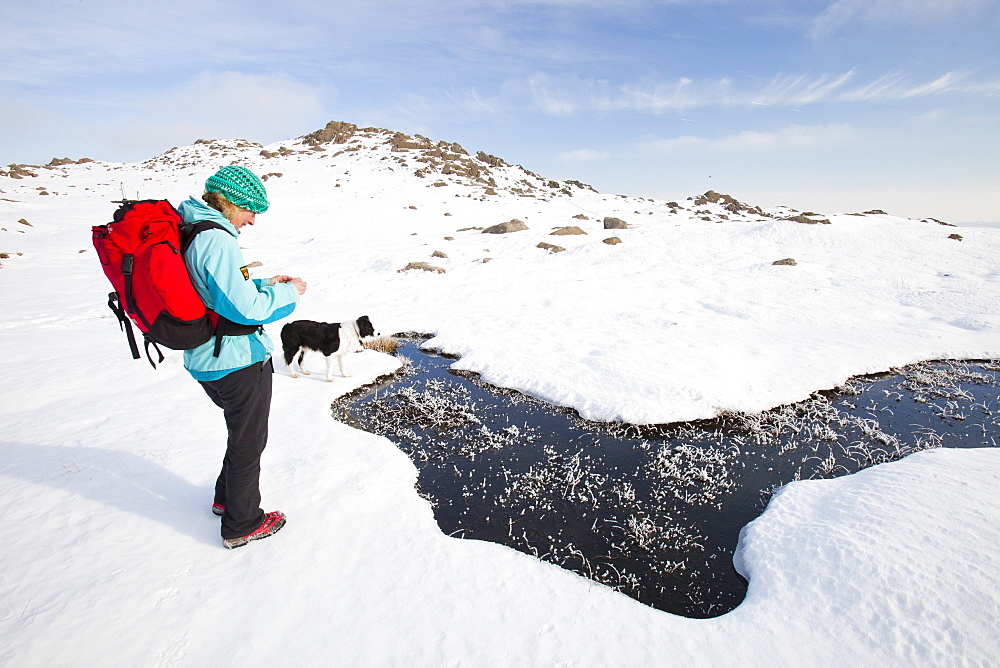 A woman hill walker by a frozen bog near Stickle Tarn in the Langdales, Lake District, Cumbria, England, United Kingdom, Europe