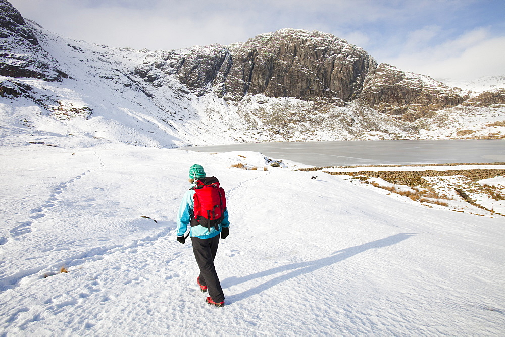 A woman hill walker by a frozen Stickle Tarn in the Langdales, Lake District, Cumbria, England, United Kingdom, Europe