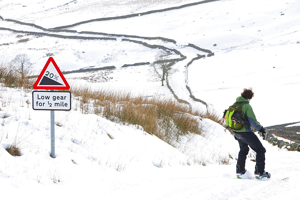 A man snow boarding down from the summit of Kirkstone Pass in the Lake District, Cumbria, England, United Kingdom, Europe