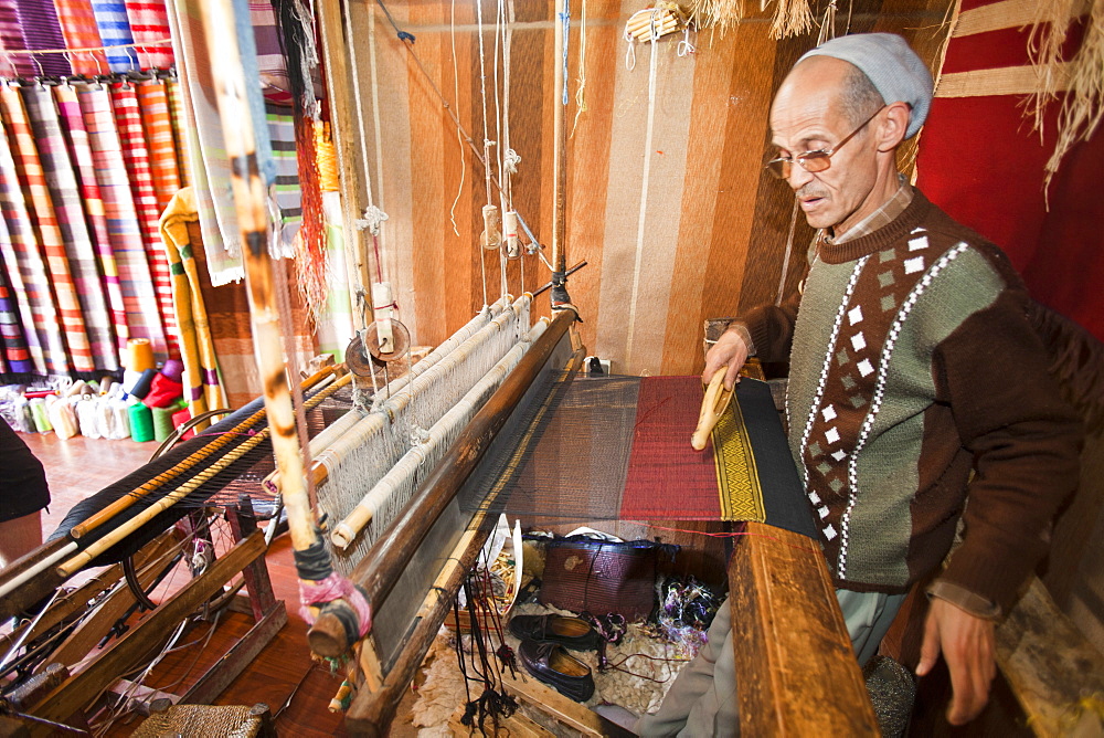 An old man working a loom to weave traditional Moroccan cloth in a souk in Marrakech, Morocco, North Africa, Africa