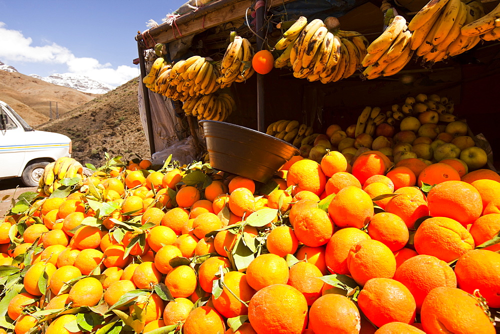 Oranges on a market stall looking up towards the snow covered peaks of the Atlas mountains, Morocco, North Africa, Africa