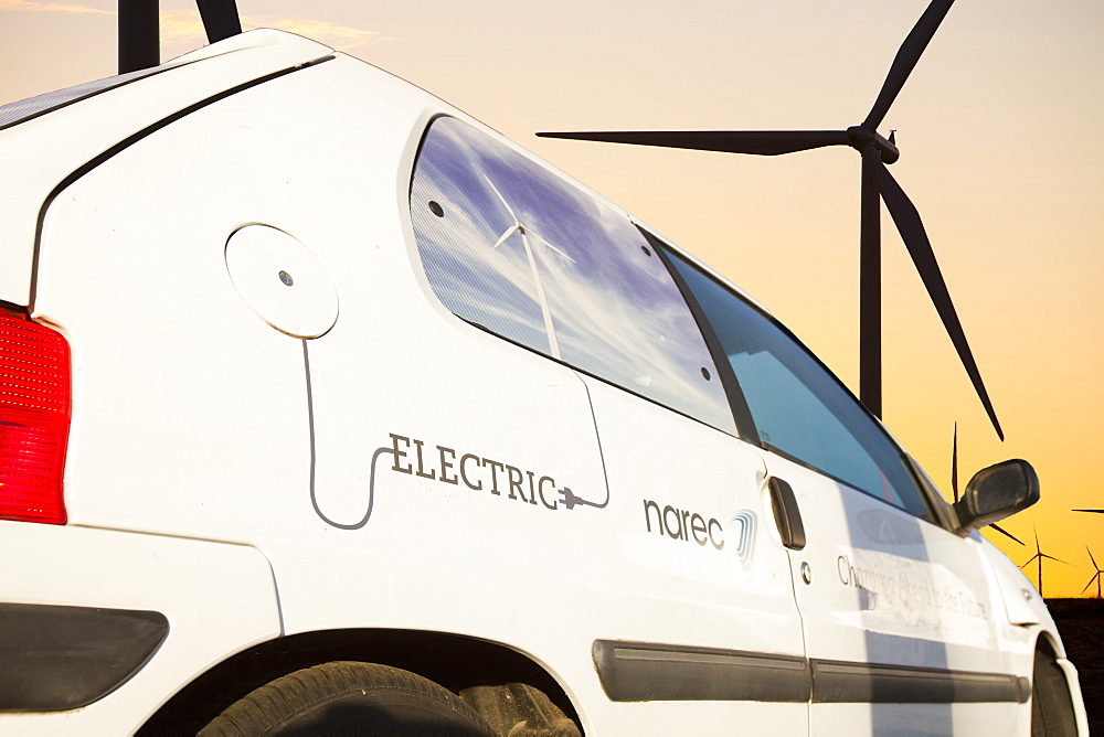 An electric car at dawn over Whitlee wind farm on Eaglesham Moor just south of Glasgow in Scotland, United Kingdom, Europe