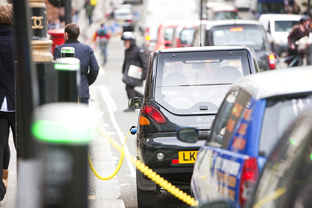 A row of electric vehicles at recharging stations on the street in Berkeley Square, London, England, United Kingdom, Europe