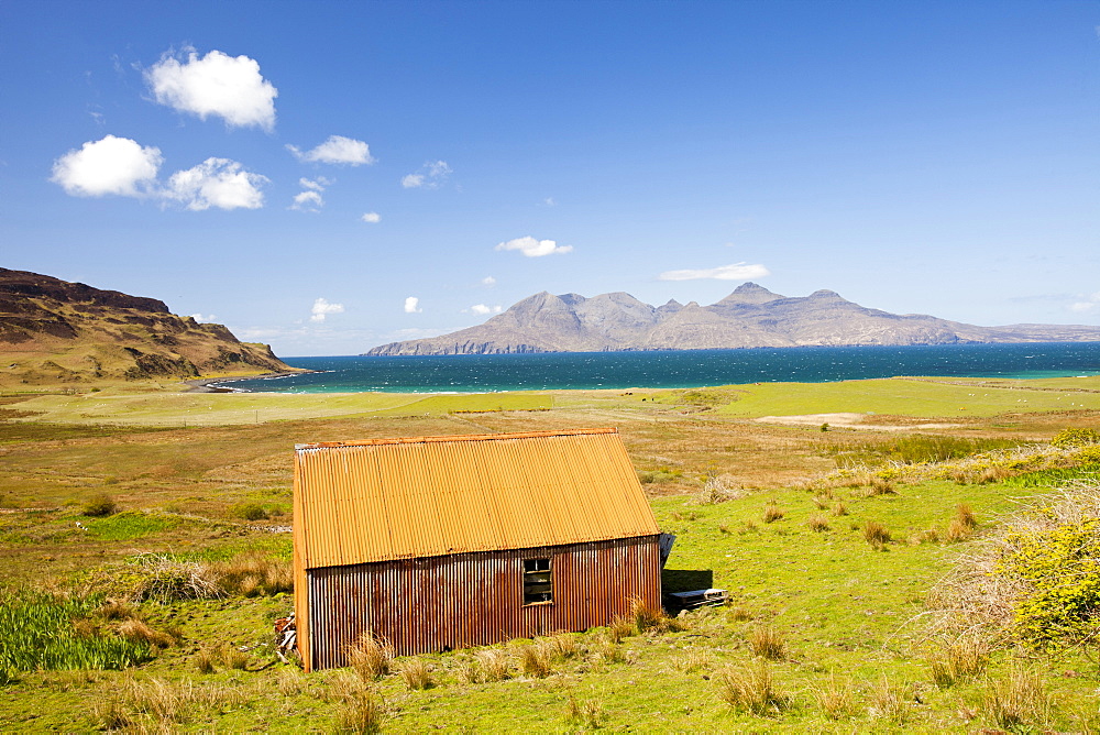 An old corrugated iron barn at Cleadale on the Isle of Eigg, looking towards the Isle of Rhum, Scotland, United Kingdom, Europe