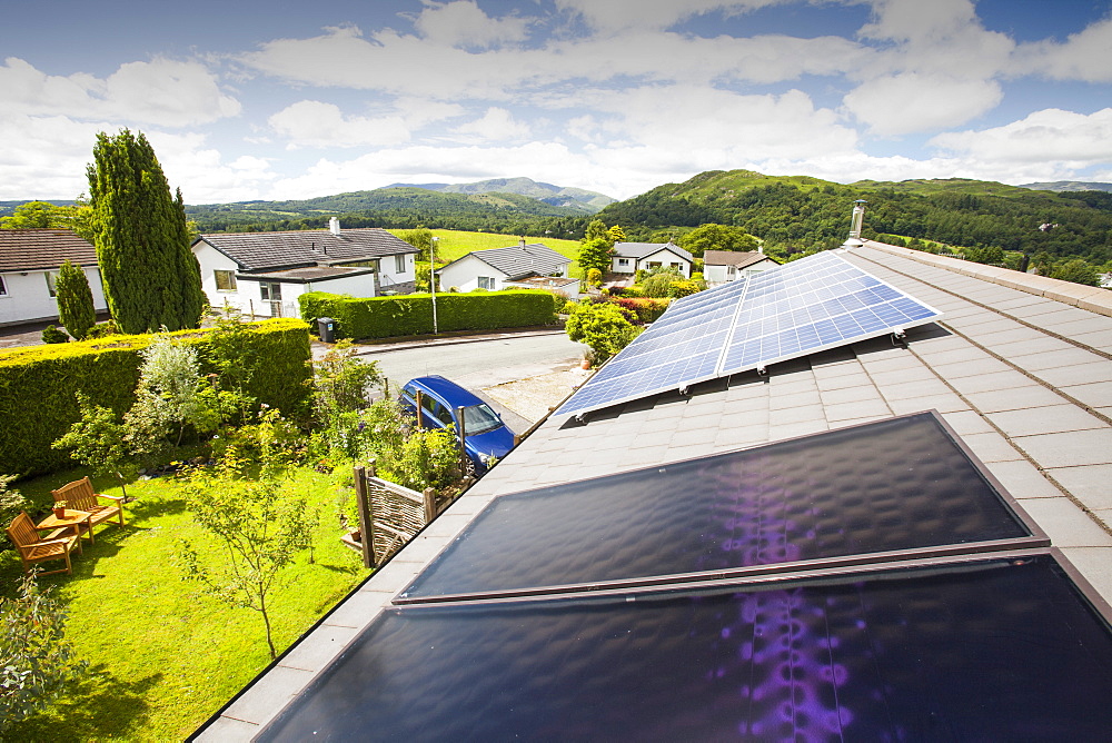 Solar thermal panels for heating hot water with solar PV electric panels behind on a house roof in Ambleside, Lake District, Cumbria, England, United Kingdom, Europe