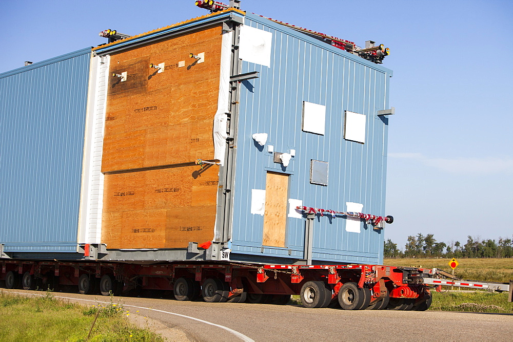 Trucks haul an oversize load of tar sands equipment for a SAGD mine, on the road towards Fort McMurray, the centre of the tar sands industry, Alberta, Canada, North America