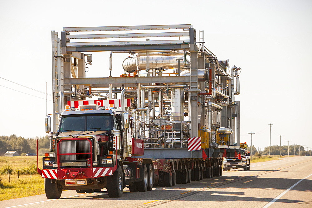 Trucks haul an oversize load of tar sands equipment for a SAGD mine, on the road towards Fort McMurray, the centre of the tar sands industry, Alberta, Canada, North America