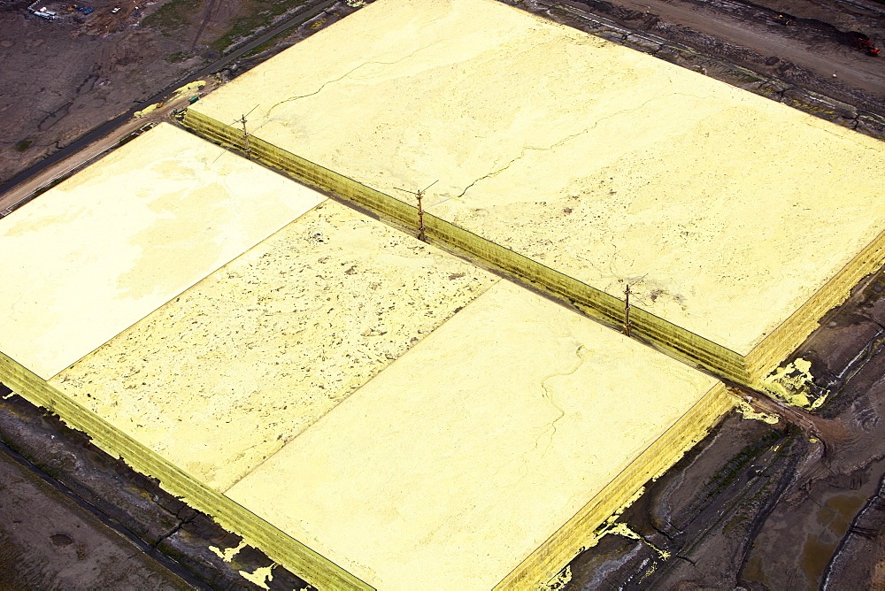 Sulphur which has to be extracted from the raw bitumen from tar sands piled up in huge mountains by the Syncrude upgrader plant near Fort McMurray, Alberta, Canada, North America