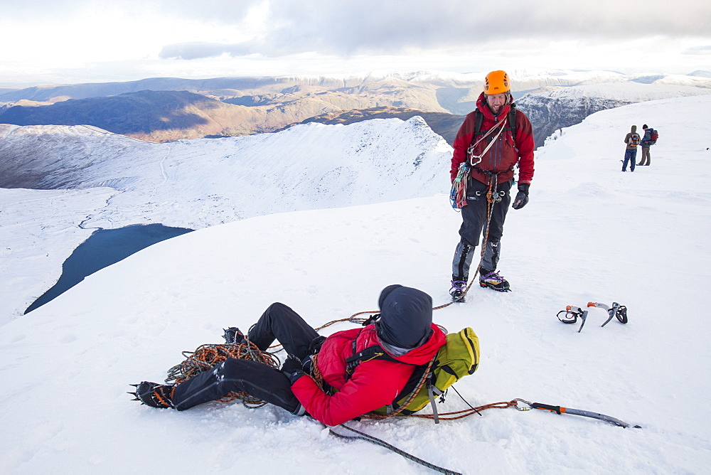 Climbers on the summit plateau of Helvellyn having just finished a route, looking down towards Red Tarn and Striding Edge, Lake District National Park, Cumbria, England, United Kingdom, Europe