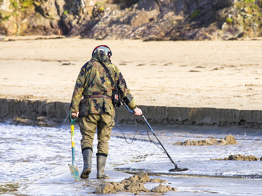 A man with a metal detector on Polzeath beach, Cornwall, England, United Kingdom, Europe