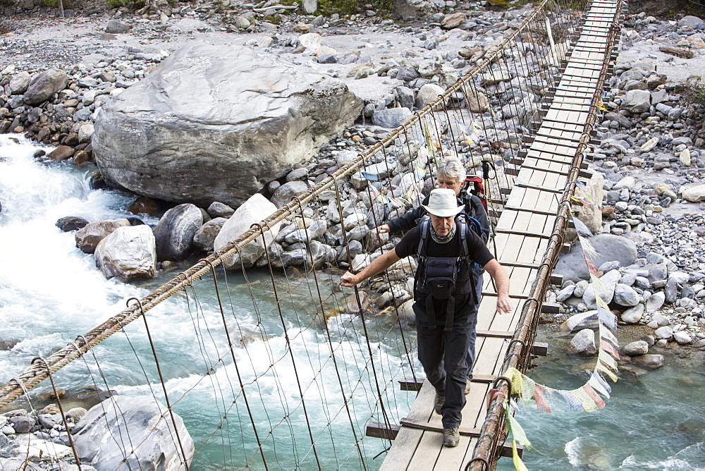 Trekkers crossing a suspension bridge crossing on the Annapurna Base Camp trek, Himalayas, Nepal, Asia