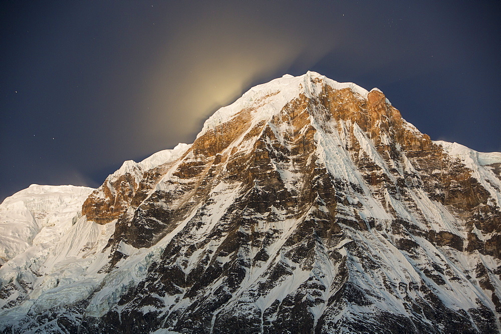 The night sky over Annapurna South in the Annapurna Sanctuary, with the glow from the setting moon behind the peak, Himalayas, Nepal, Asia