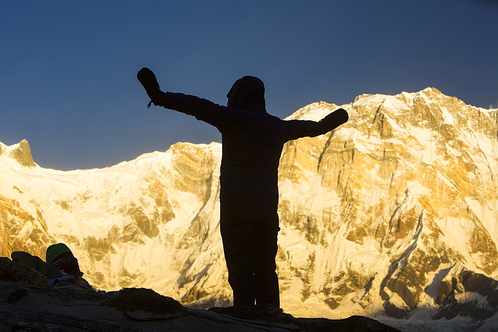 A trekker with alpenglow at sunrise on Annapurna South and Annapurna Fang, Nepalese Himalayas, Nepal, Asia