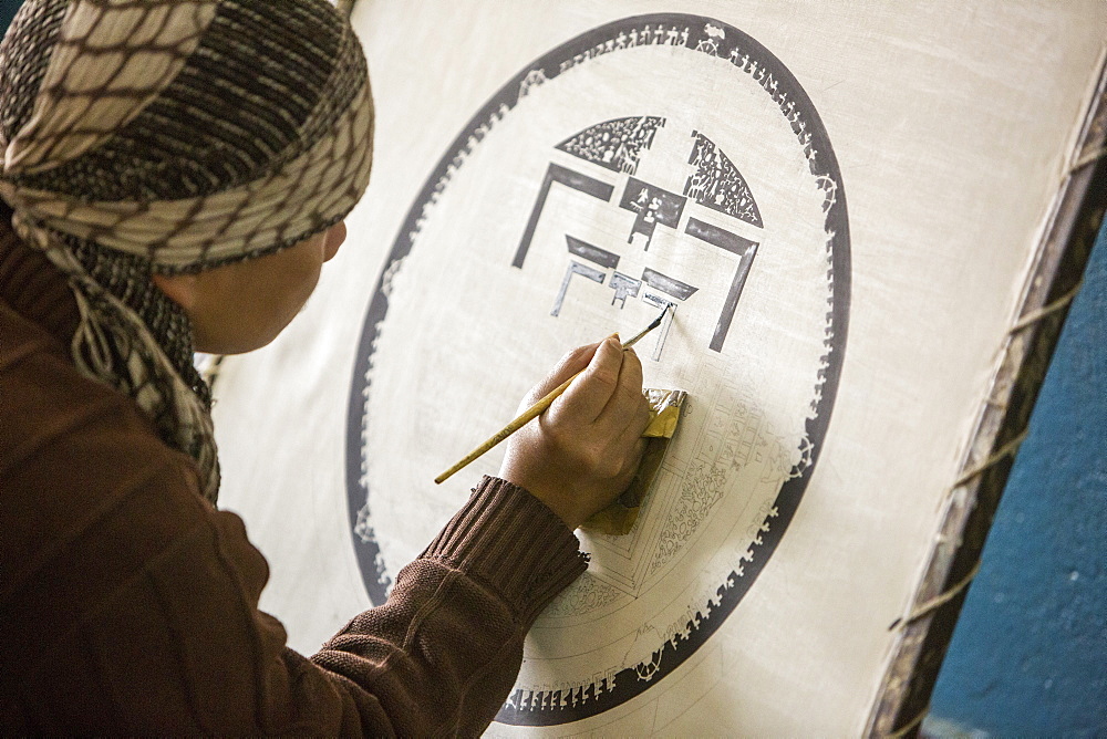 A Buddist artist painting a traditional Thanka painting at the Boudhanath Stupa, one of the holiest Buddhist sites in Kathmandu, Nepal, Asia