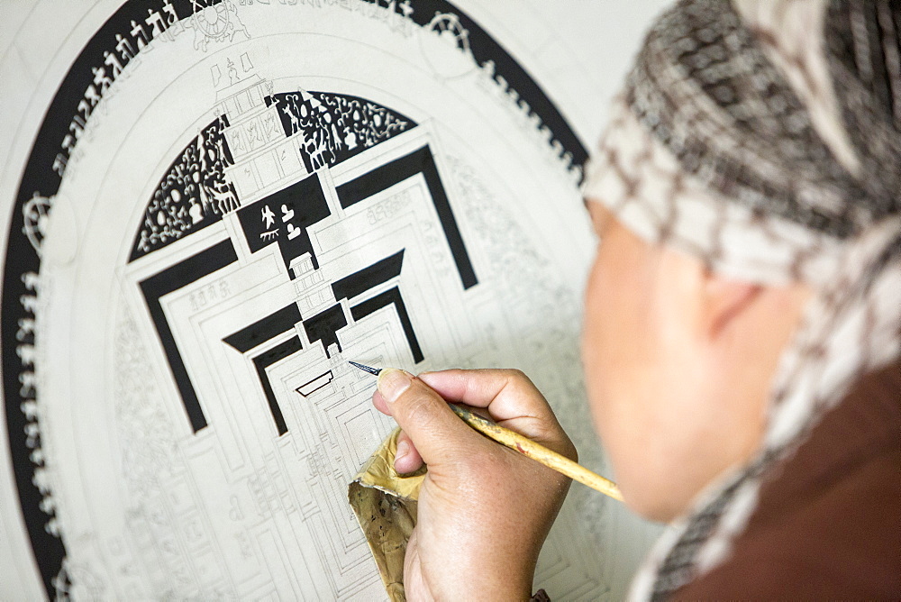 A Buddist artist painting a traditional Thanka painting at the Boudhanath Stupa, one of the holiest Buddhist sites in Kathmandu, Nepal, Asia