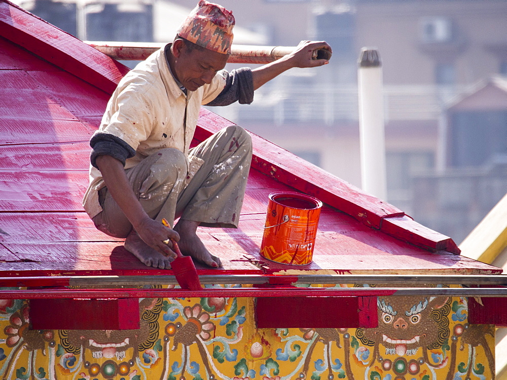 A man precarioulsy balanced at height, painting a building in Kathmandu, Nepal, Asia