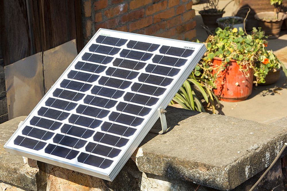 A tiny solar photo voltaic panel on a rooftop in Kathmandu, big enough to power a couple of lights in the house below, Nepal, Asia