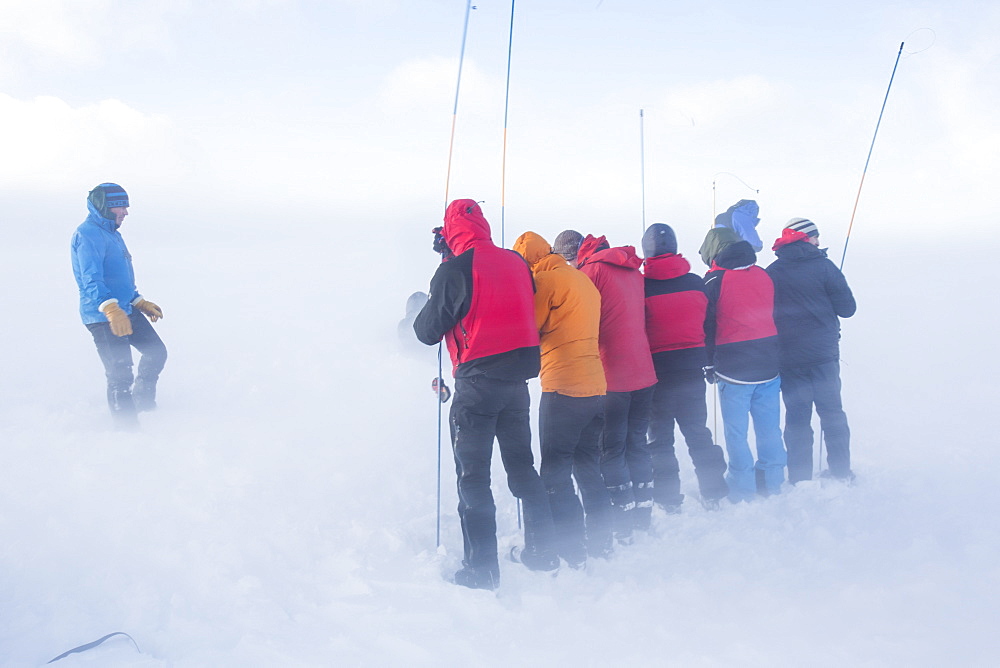 Drifting snow in Coire an Sneachda covers mountaineers training to use avalanche probes in the Cairngorm mountains, Scotland, United Kingdom, Europe