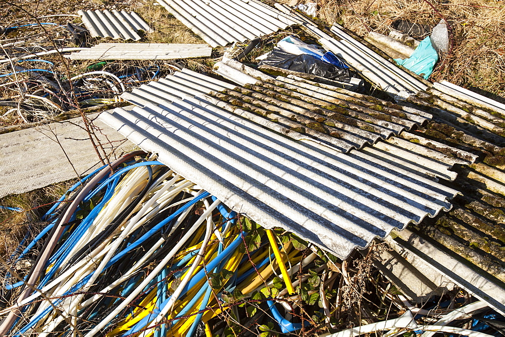 Illegally dumped asbestos sheeting with plastic wire sheath left by metal theives who stole the cabling and stripped the plastic off to get at the valuable copper wire, England, United Kingdom, Europe