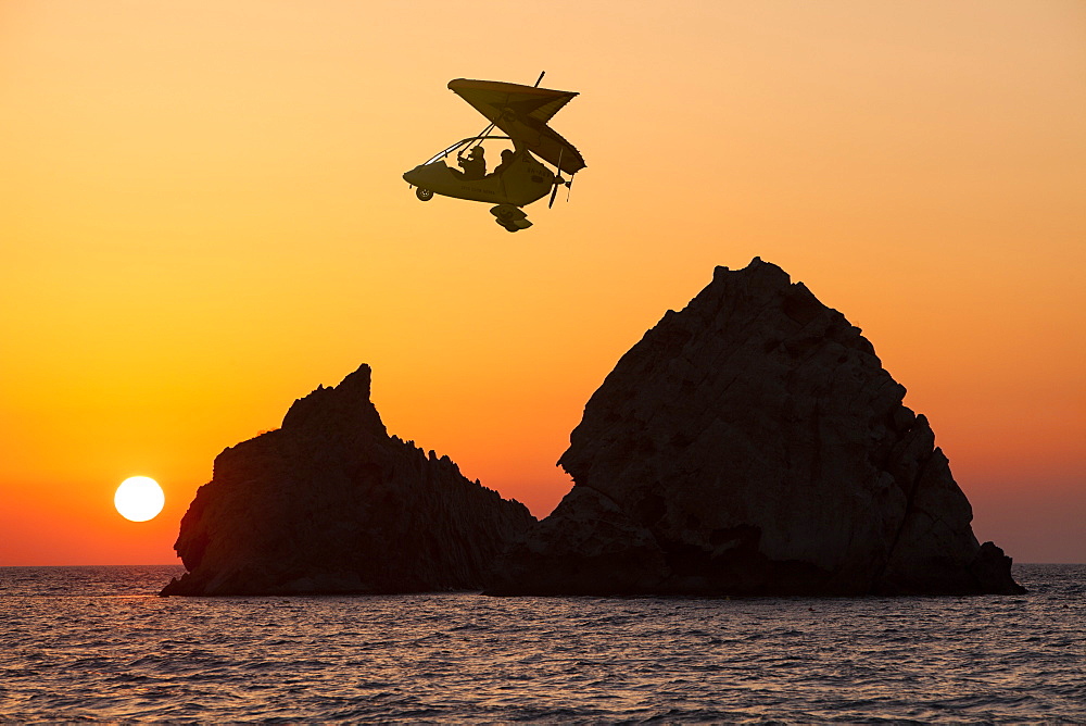 Motorised hang glider at sunset over rocky islands off Myrina on Lemnos, Greek Islands, Greece, Europe