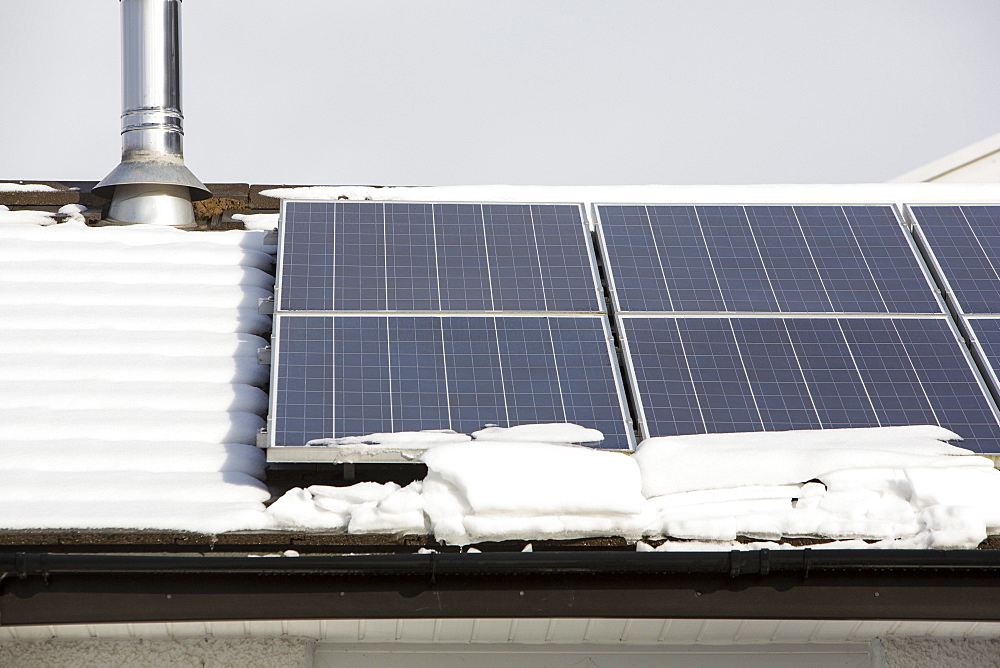 Solar panels partially covered in snow on a house roof in Ambleside, Lake District, Cumbria, England, United Kingdom, Europe