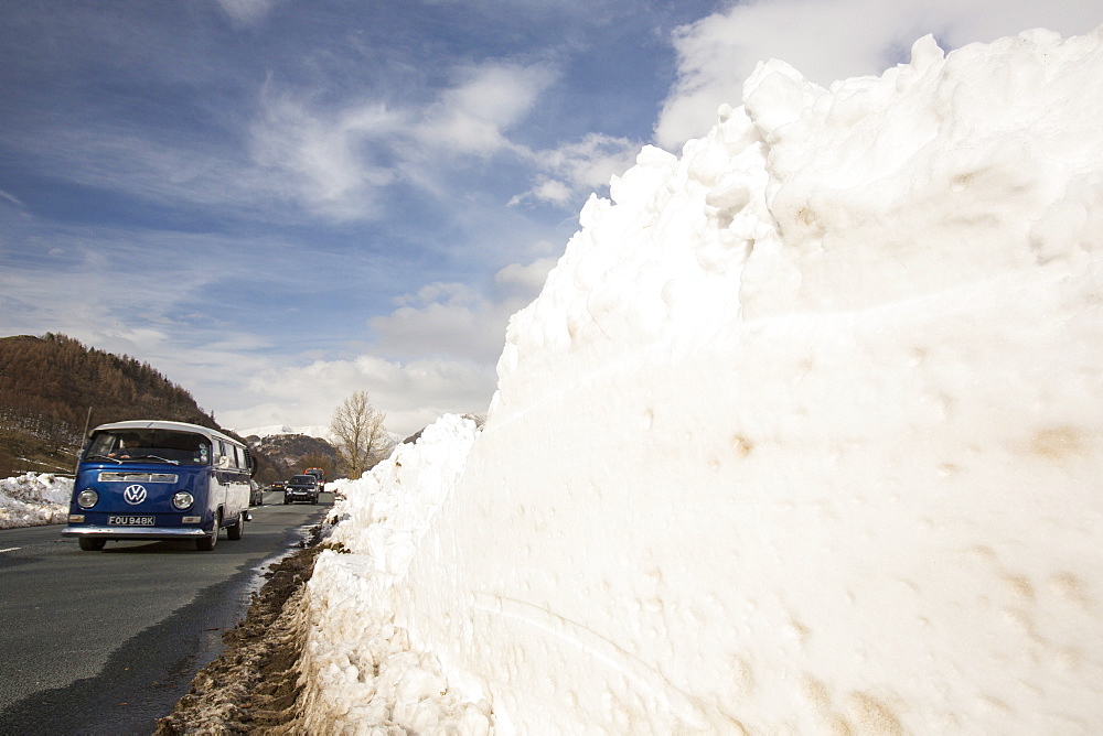 Traffic passes snowdrifts below Helvellyn during the extreme winter weather in late March 2013, Lake District, Cumbria, England, United Kingdom, Europe