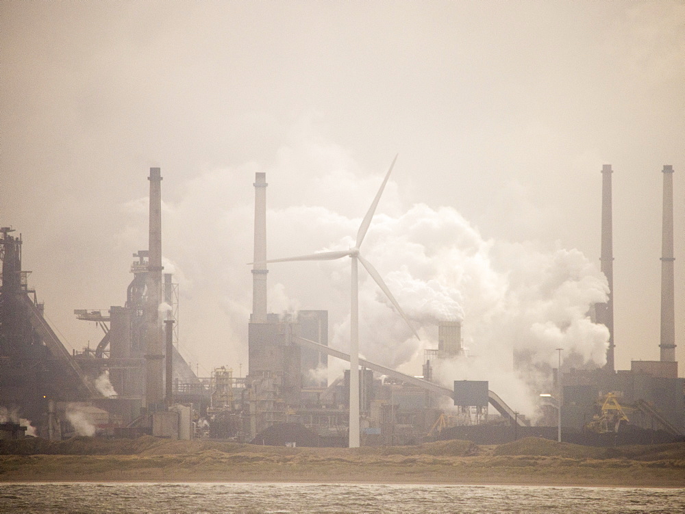 Climate change heaven and hell, emissions from a Tata steel works in Ijmuiden, with a wind turbine, Netherlands, Europe