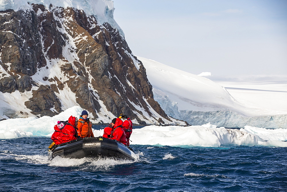 Members of an expedition cruise to Antarctica in a Zodiak off Madder Cliffs on the Antarctic Peninsular. The Antarctic Peninsular is one of the most rapidly warming areas on the planet.