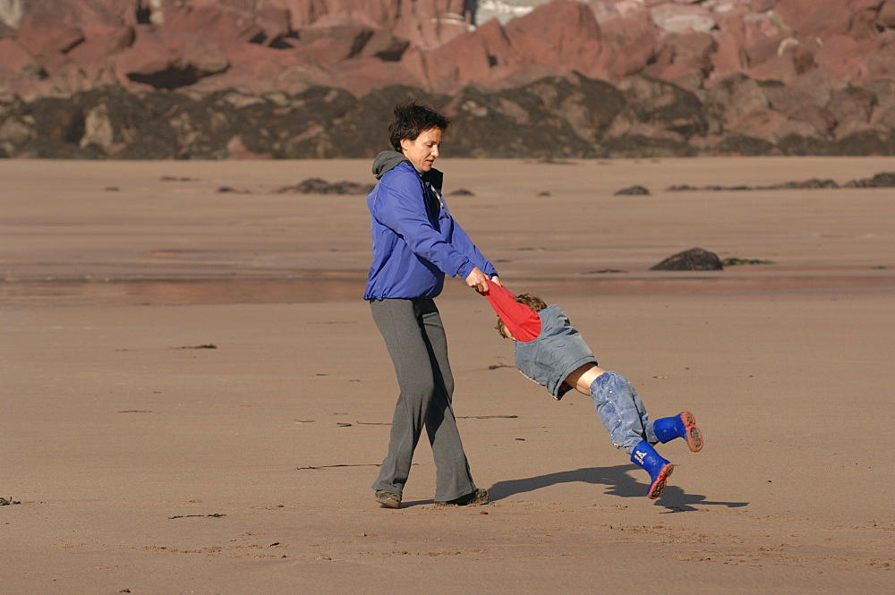 Mother spinning son around, West Dale beach, Dale, Pembrokeshire, Wales, UK, Europe