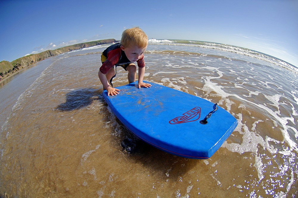 Young boy playing with boogie board on beach