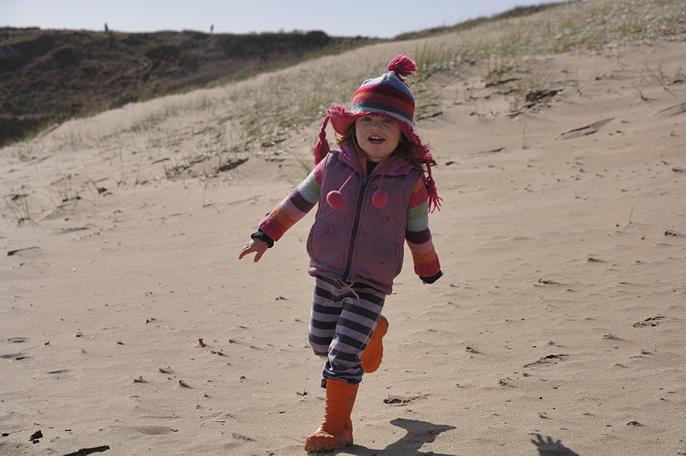 Young girl running in sand dunes,  Broad Haven South, Stackpole, Pembrokeshire, Wales, UK, Europe