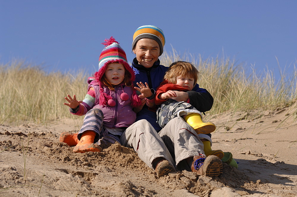 Mother and son and daughter playing in sand dunes, Broad Haven South, Stackpole, Pembrokeshire, Wales, UK, Europe