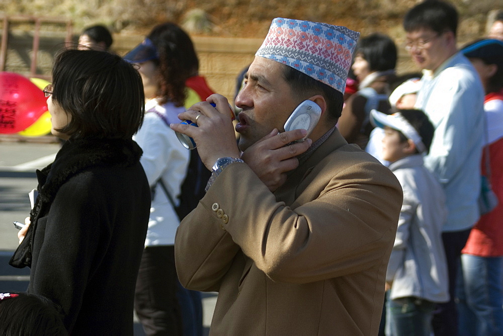 Nepalese drinking soda and talking on cell phone simultaneously, Geoje-Do, South Korea, Asia