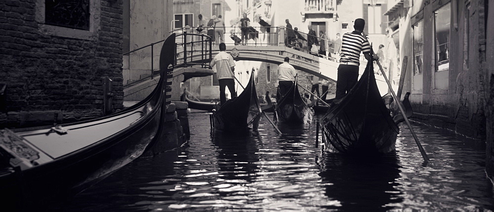 Gondalas going under a bridge. Venice, Italy