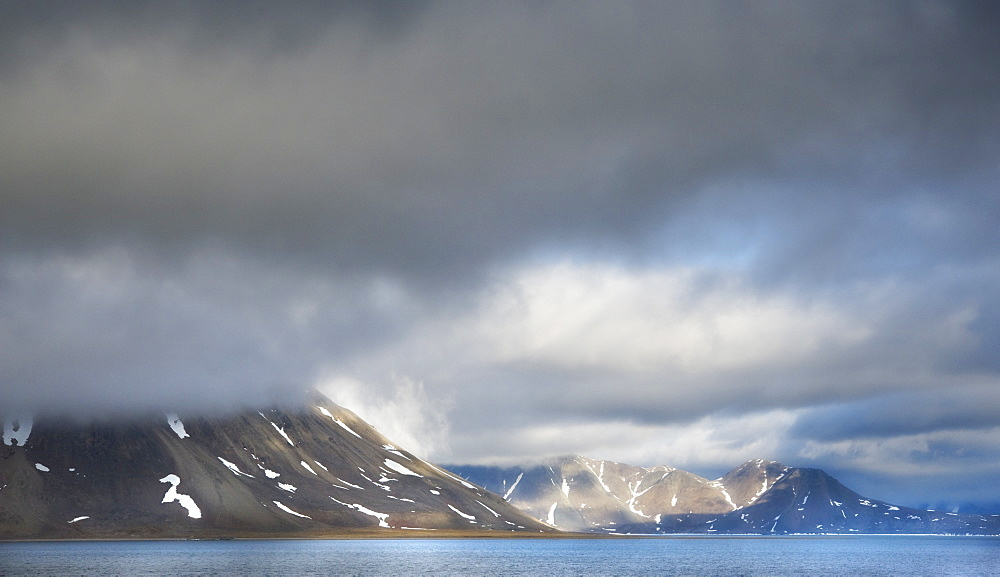 Landscape scenic view with snow caped mountains, ocean, and clouds, Penkigney Fjord (Bering Sea ) Russia, Asia