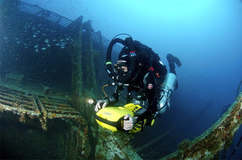 Mixed gas rebreather diver using scooter for mobility inside wreck.  Red Sea.