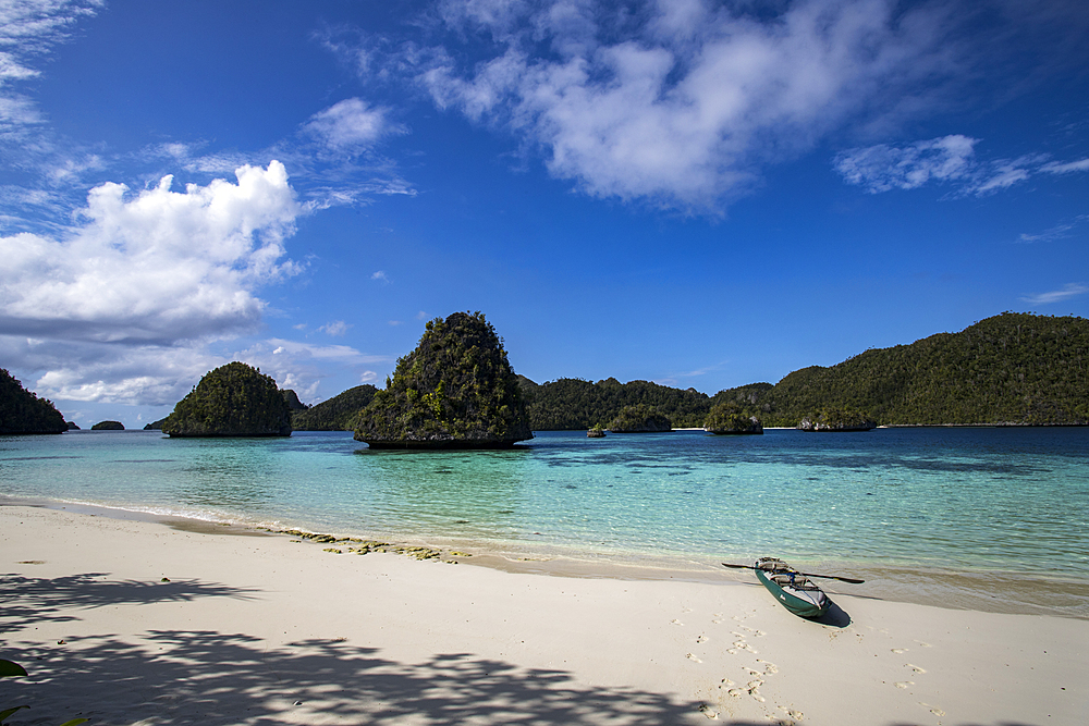 Karst limestone formations and lagoon in Wayag Island with the photographer's kayak, Raja Ampat, West Papua, Indonesia, Southeast Asia, Asia