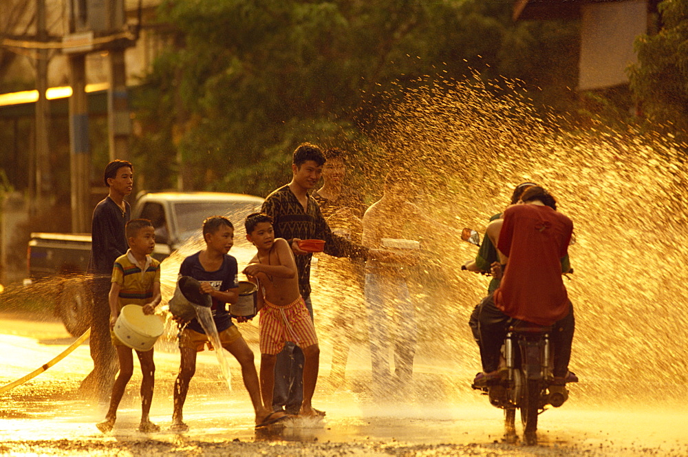 People on a motorbike being showered with water by men and boys during the Songklan Festival in Thailand, Southeast Asia, Asia