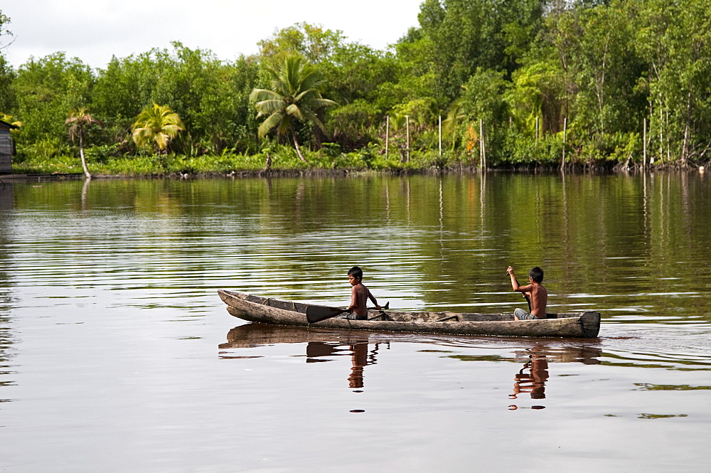 Amerindian boys paddling dugout canoe, Maharuma, Guyana, South America