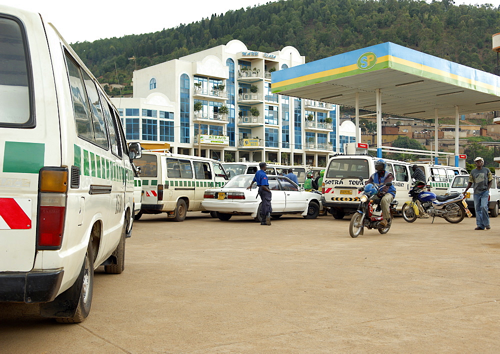 Running out of Petrol is commonplace in Rwanda.  Here, a petrol station in Kigali is filling up with vehicles but are having little joy with sourcing any petrol.  The ubiquitous armed security guard casually stands watching the chaos. Kigali, Rwanda, East Africa