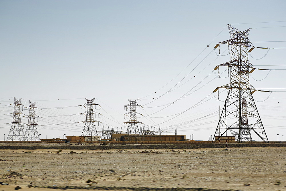 Electricity pylons dominate the flat barren landscape, pointing to civilisation somewhere, Qatar, Middle East