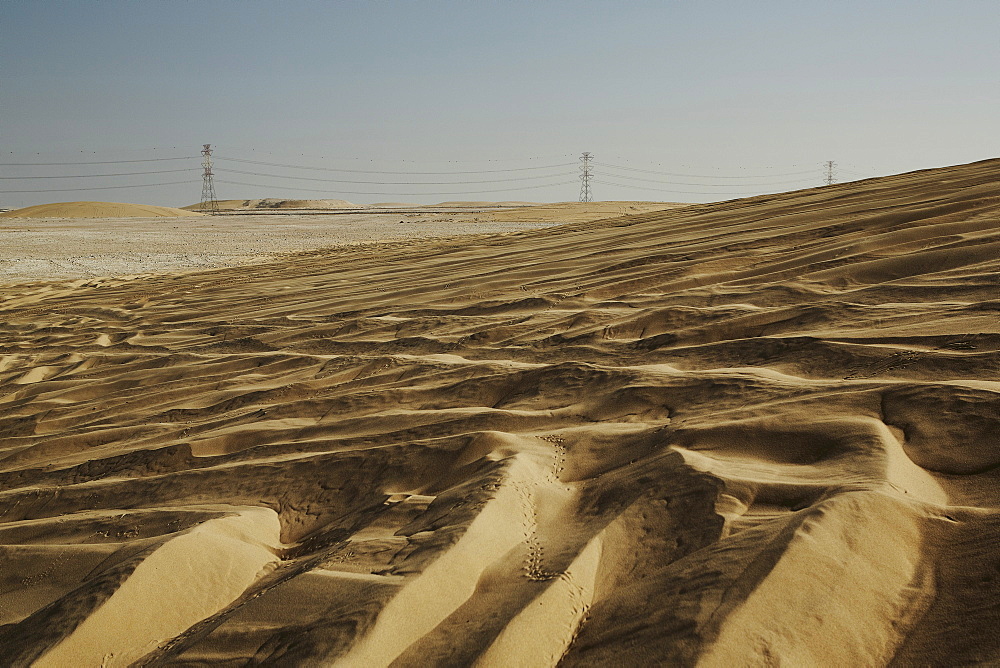 Sand dunes and electricity pylons dominate the desert landscape, Qatar, Middle East