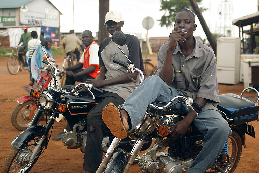 In the North West of Uganda is Gulu District.  These bikers are relaxing between errands in the centre of Gulu town. Gulu Town, Uganda, East Africa