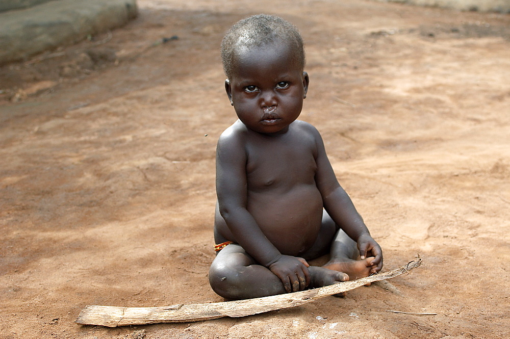 An IDP camp (internally displaced people) in Amuru district of Northern Uganda has been created to accommodate the mass of Ugandan refugees fleeing the LRA (Lords Resistance Army) who are fighting the Ugandan government and its people.  Here a young child has found a stick to play with. Amuru, Uganda, East Africa