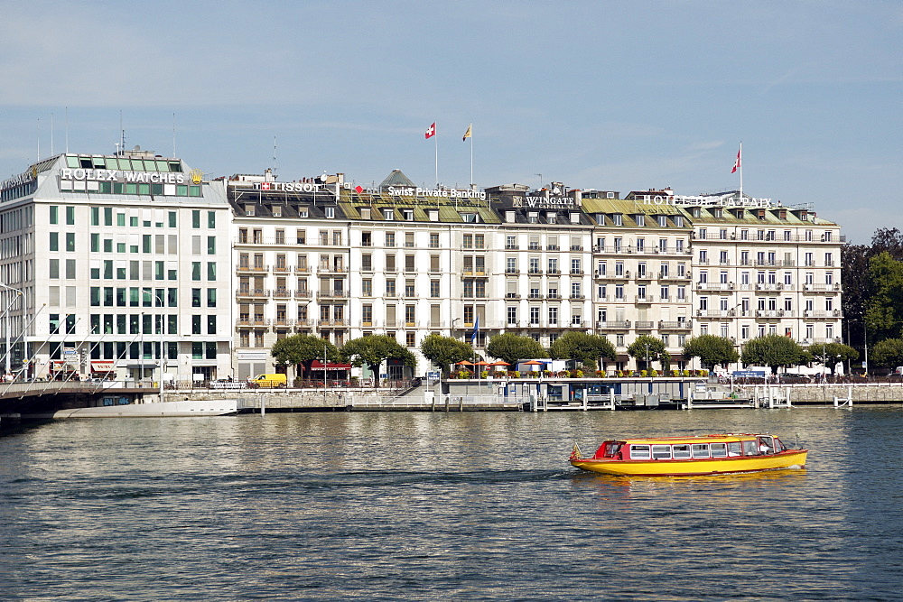 Tourist river boat cruises past luxury brand companies on Quai du Mont Blanc, Geneva. Geneva, Switzerland