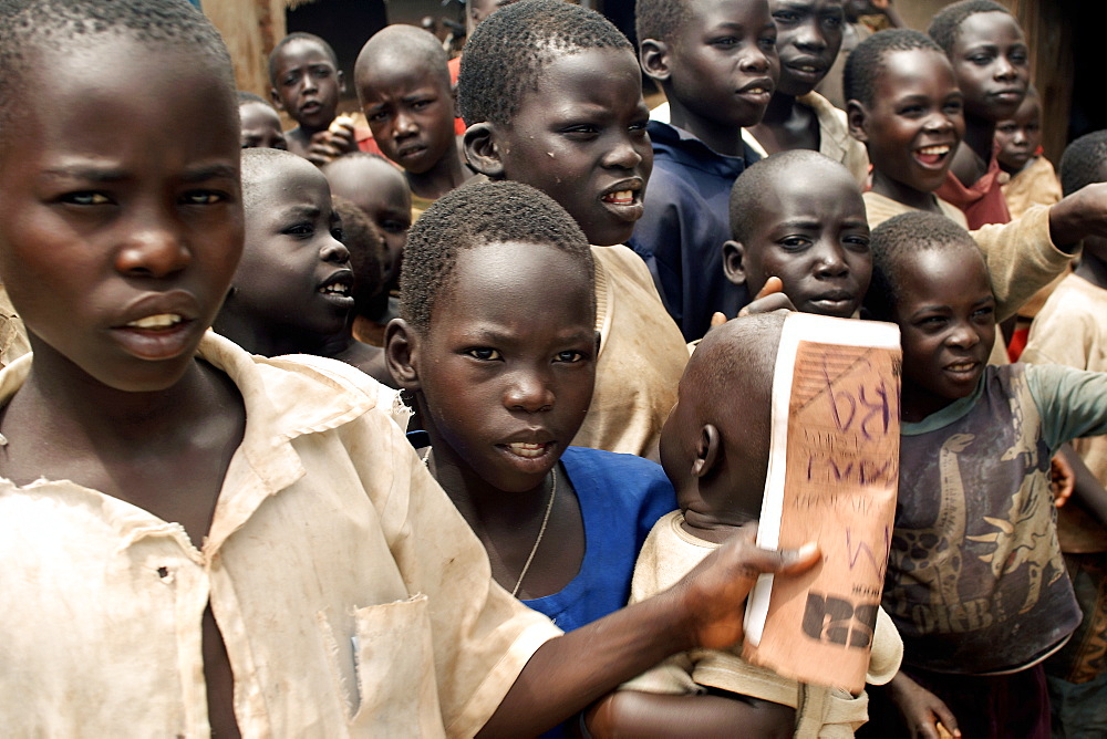 An IDP camp (internally displaced people) in Amuru district of Northern Uganda has been created to accommodate the mass of Ugandan refugees fleeing the LRA (Lords Resistance Army) who are fighting the Ugandan government and its people.  An inquisitive teenage boy is holding an exercise book. Amuru, Uganda, East Africa