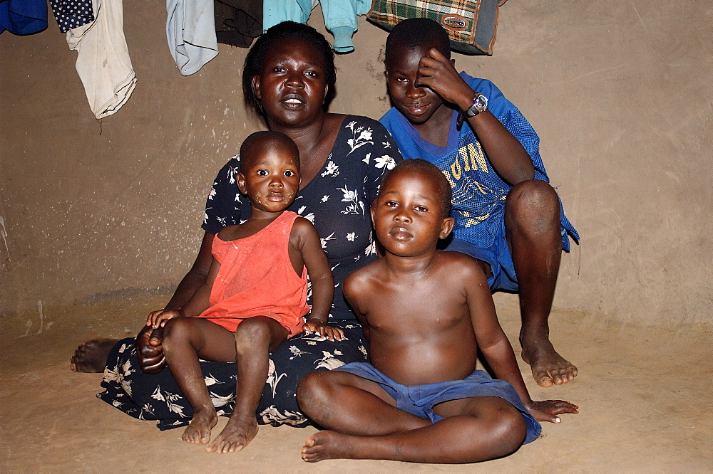 Inside a typical mud hut, commonly found in Gulu Town, Northwest Uganda.  Family are without father who is out working during the day. Gulu Town, Uganda, East Africa