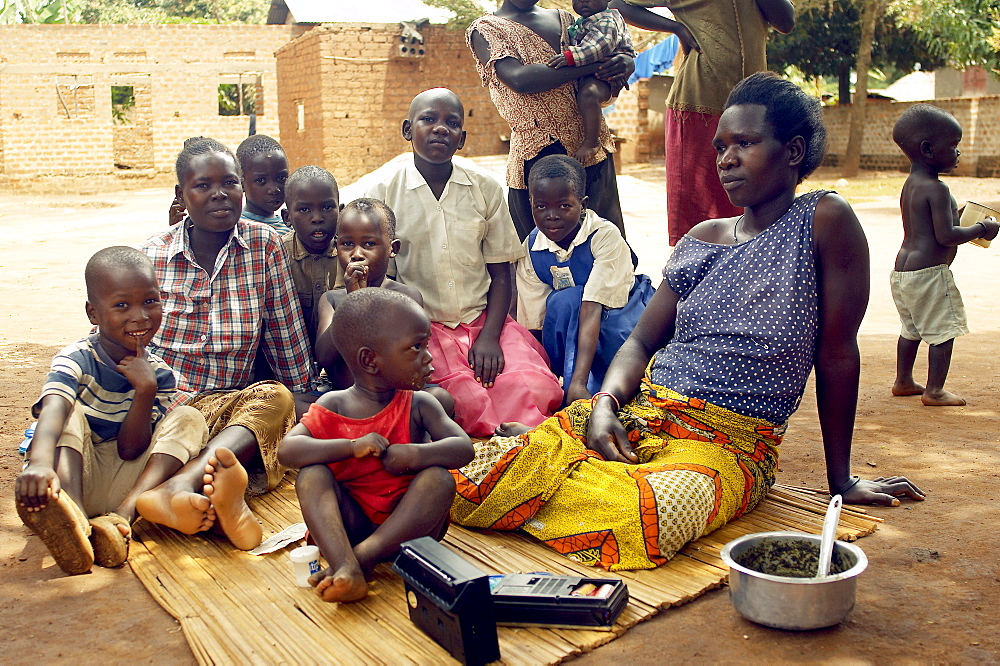 Time off from domestic chores and hard core playing, mothers rest in the shade with their children, listening to the radio. Gulu Town, Uganda, East Africa