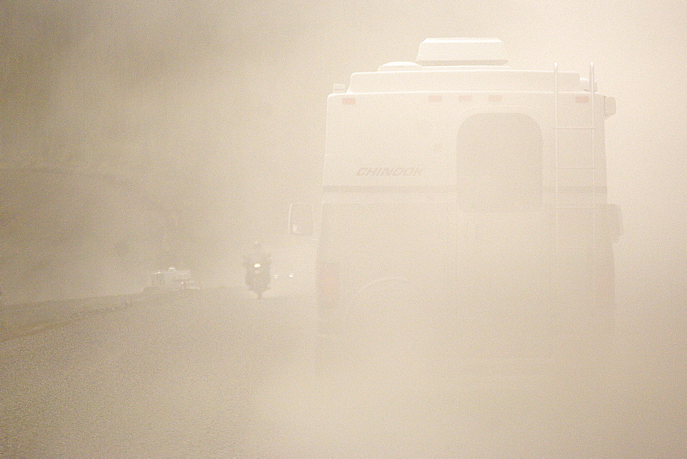 Following an RV through a heavy cloud of dust generated by heavy traffic on a gravel road.  Clearly see is a motorbike coming towards us on other side of the road. The Interior, Alaska, USA